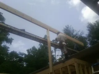 Carpenter setting a ridge beam over a new addition frame — Ice Dam Removal by Roofing Brothers in Century