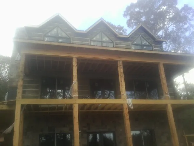 Dormers and porch framing on a large log home under construction — Roof Coating work by our crew in Century