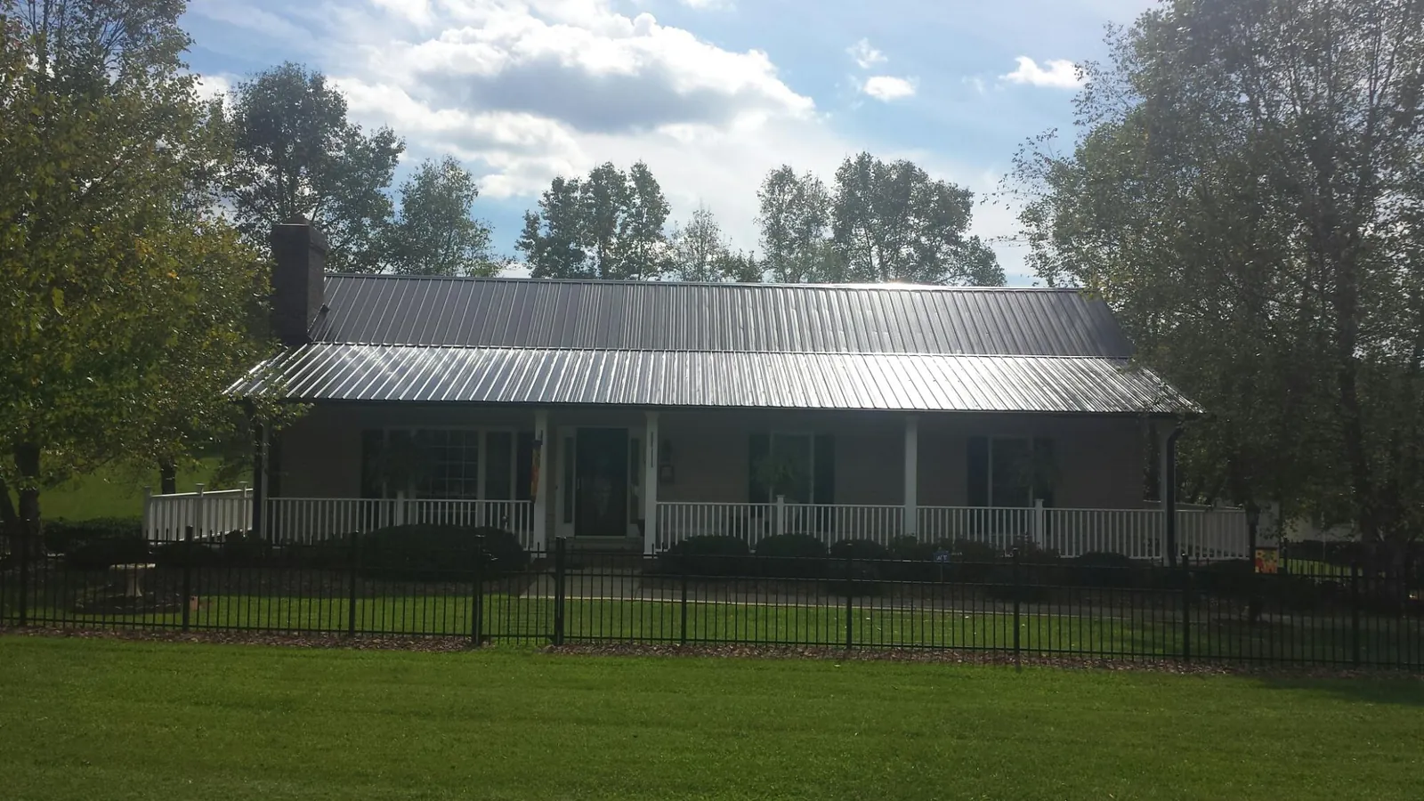 Gray metal roof on a brick ranch with a full width front porch — Gutter Guard Installation work by our crew in Century