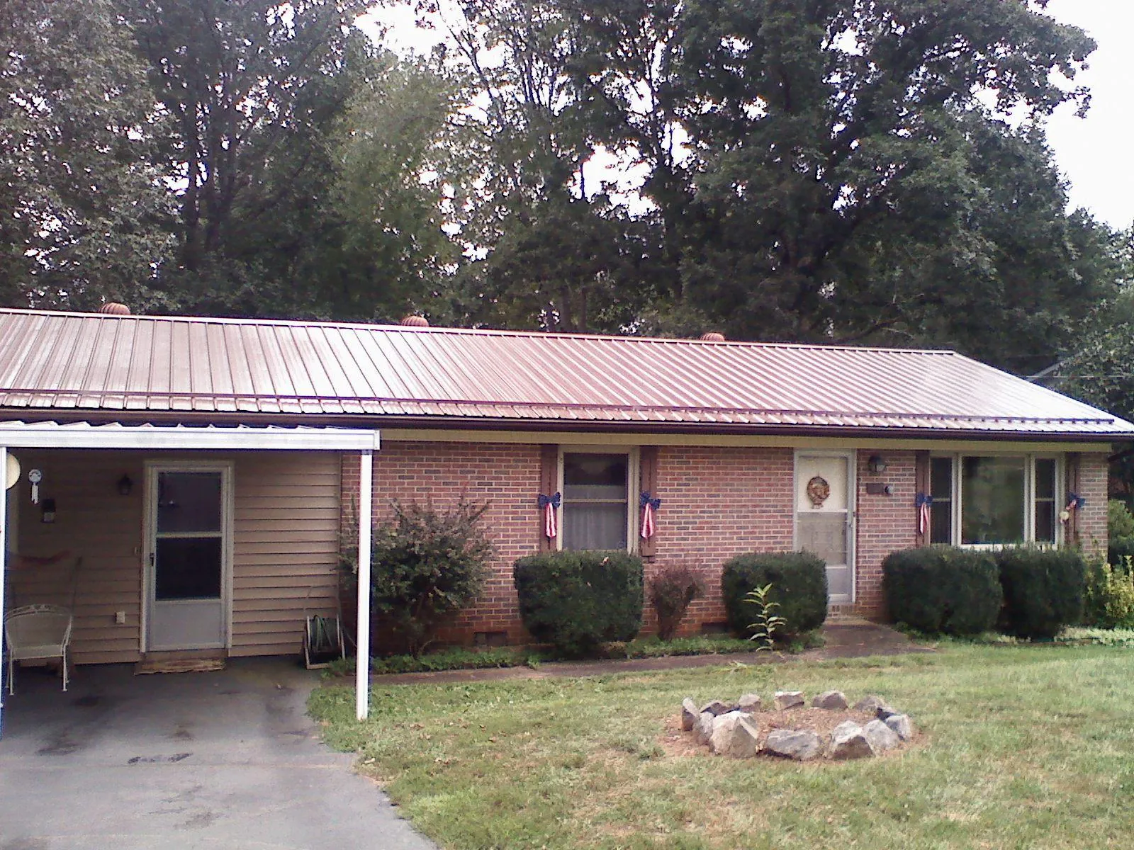 Bronze metal roof and carport on a brick ranch home — Roof Repair work by our crew in Century